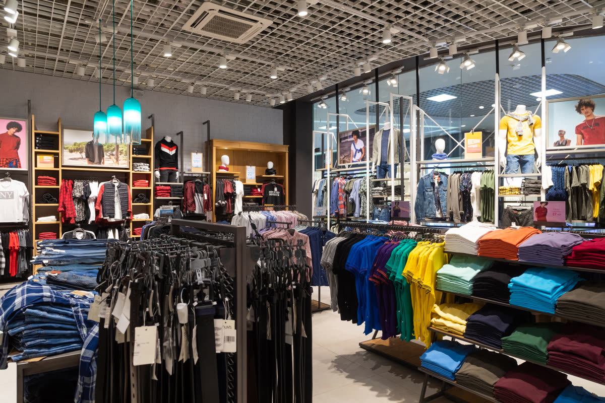 Modern clothing retail store interior with clothing racks, folded apparel displays, and mannequins